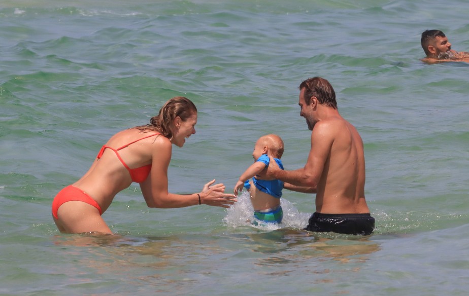 Roger Flores e Betina Schmidt com o pequeno Tom na praia da Barra da Tijuca, no Rio