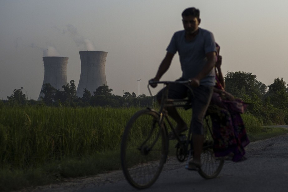 Homem pedala perto de usina termoelétrica em Budh Nagar, na província indiana de Uttar Pradesh