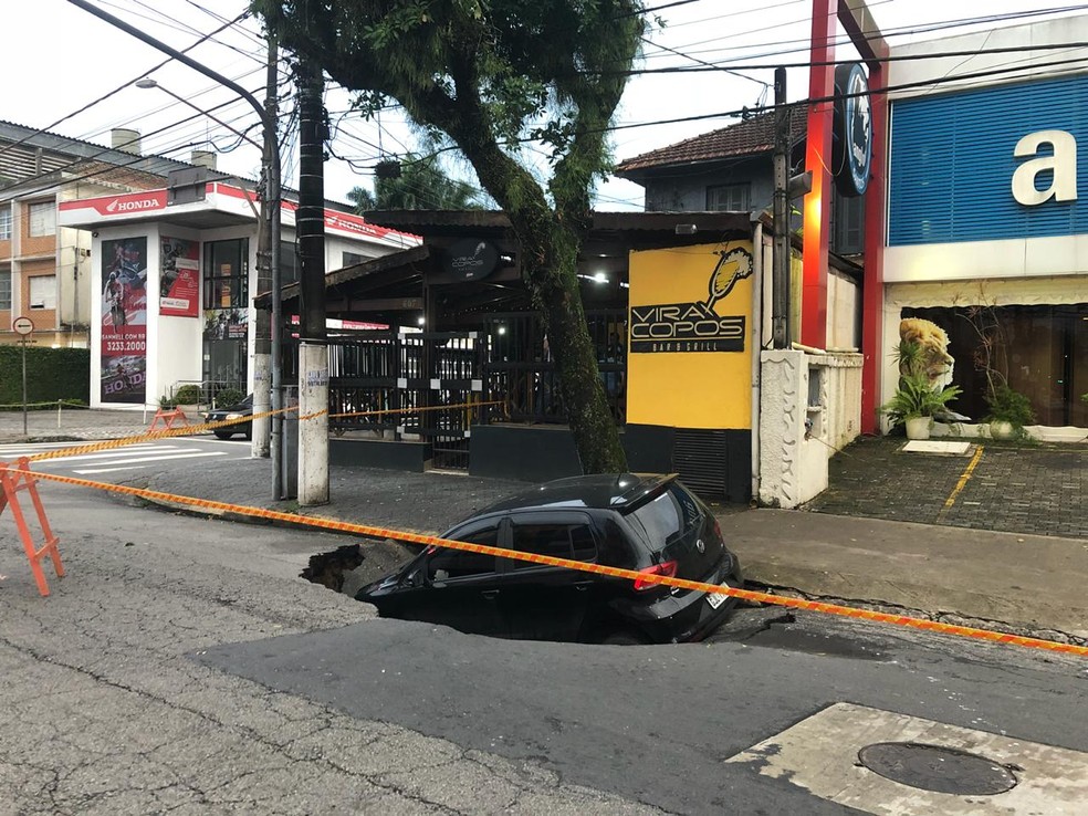 Carro é 'engolido' por cratera que abriu em avenida de Santos (SP) — Foto: Andressa Barboza/G1