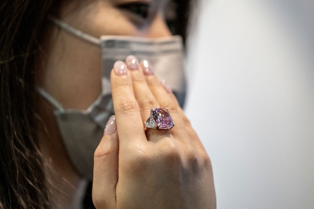 A woman displays the Sakura Diamond during preview at Christie's in Hong Kong, China, 20 May 2021. The 15.81 Carat Fancy Vivid Purple Pink Internally Flawless Type lla Diamond Ring will be auctioned in Hong Kong on 23 May 2021 for an estimated 25 million  (Foto: NurPhoto via Getty Images)