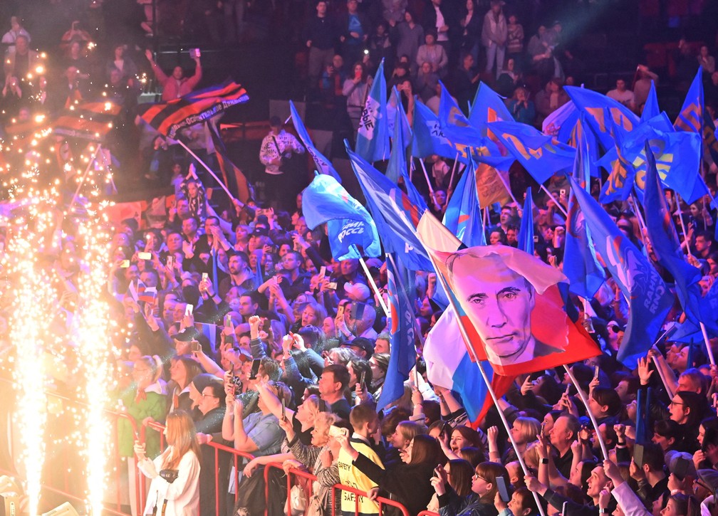 Manifestantes agitam bandeiras, incluindo uma com o rosto do presidente russo, Vladimir Putin, durante um show marcando o Dia Internacional dos Trabalhadores em Omsk, segunda maior cidade do país. — Foto: REUTERS/Alexey Malgavko