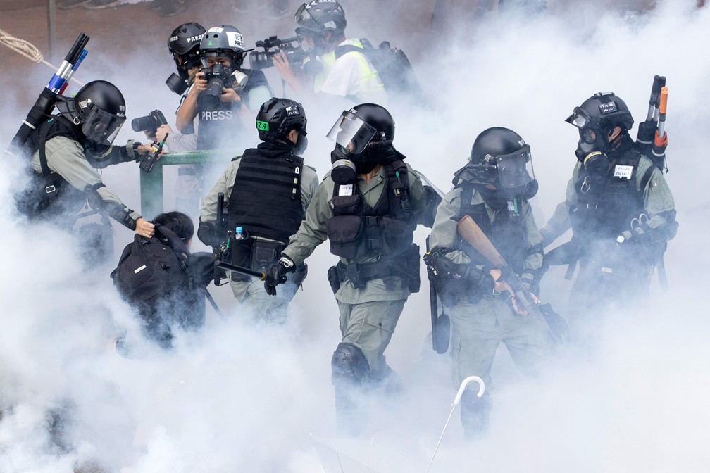 18 de novembro - Policiais da tropa de choque se movimentam em meio a uma nuvem de fumaça enquanto prendem um manifestante na Universidade Politécnica de Hong Kong. Os protestos no território semiautônomo começaram em junho contra um projeto de lei que permitia a extradição de suspeitos de crimes para a China continental e continuaram nos meses seguintes. Os manifestantes criticam, entre outras coisas, a crescente influência da China na antiga colônia britânica — Foto: Ng Han Guan/AP/Arquivo