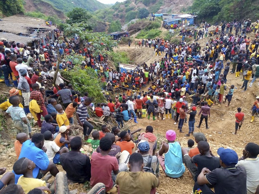 Pessoas acompanham a tentativa de resgate de ao menos 50 trabalhadores desaparecidos após mina desabar no Congo — Foto: STRINGER / AFP