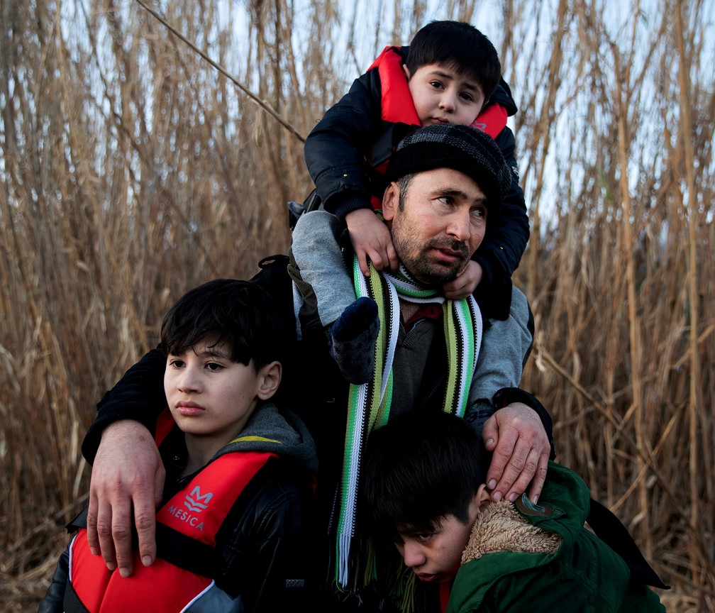 2 de março - Imigrante afegão carrega seus três filhos após cruzar o Mar Egeu, vindo da Turquia, e conseguir chegar à ilha de Lesbos, na Grécia. — Foto: Alkis Konstantinidis/Reuters