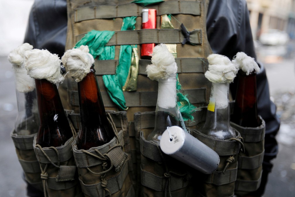 12 de dezembro - Um manifestante iraquiano carrega várias garrafas de coquetel molotov durante protesto contra o governo em Bagdá, no Iraque — Foto: Khalid al-Mousily/Reuters