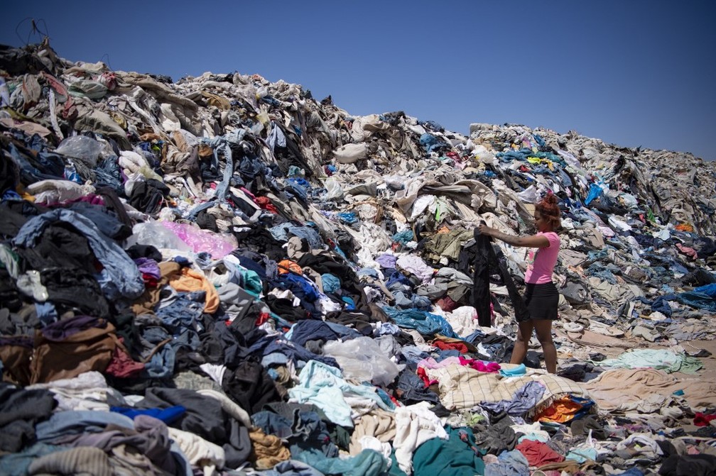 Mulheres procuram roupas em meio a descarte em Alto Hospicio, no deserto do Atacama — Foto: Martin Bernetti/AFP