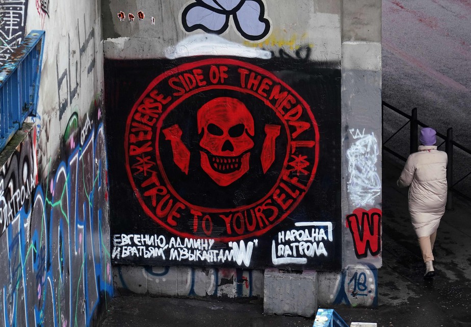 Mulher passa por mural representando a logo do grupo mercenário russo Wagner em Belgrado, Sérvia