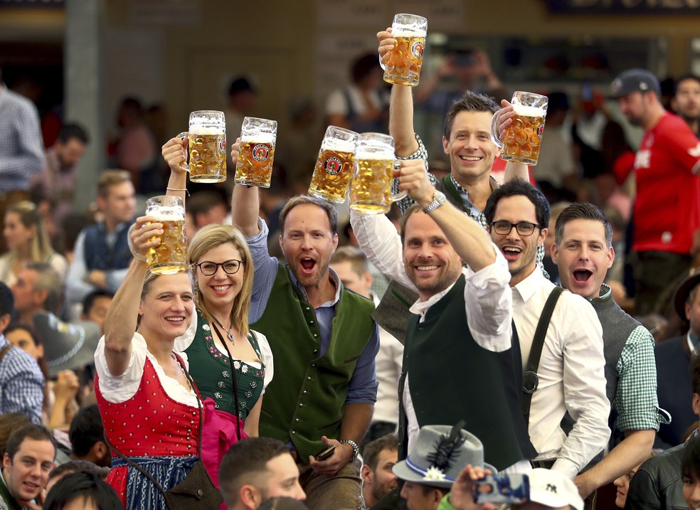 Visitantes comemoram enquanto bebem na Oktoberfest em Munique — Foto: Matthias Schrader/AP