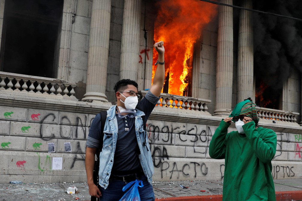 Manifestante faz gesto diante de janela incendiada no Congresso da Cidade da Guatemala neste sábado (21) — Foto: Luis Echeverria/Reuters