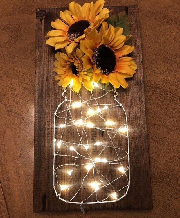 Luzinhas moldadas no formato de um vaso 'apoiam' girassóis artificiais (Foto: Reprodução/Pinterest)