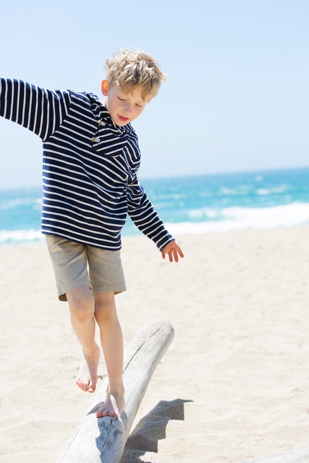 positive happy boy walking on the old trunk at the beach being active and playful at the beach (Foto: Getty Images/iStockphoto)