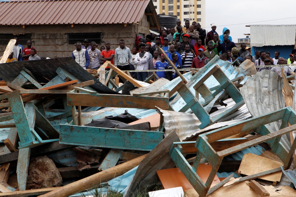 Quenianos observam sala de aula que desabou em Nairobi nesta segunda-feira (23)   â Foto: Njeri Mwangi/ Reuters