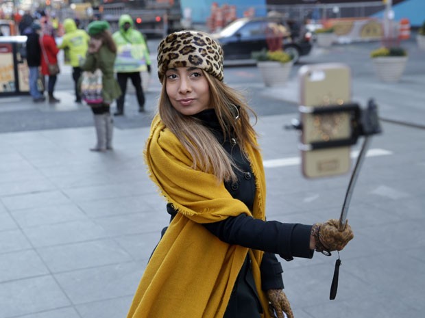 Turista tira foto de si mesma na Times Square, em Nova York, usando o 'pau de selfie' (Foto: Seth Wenig/AP)