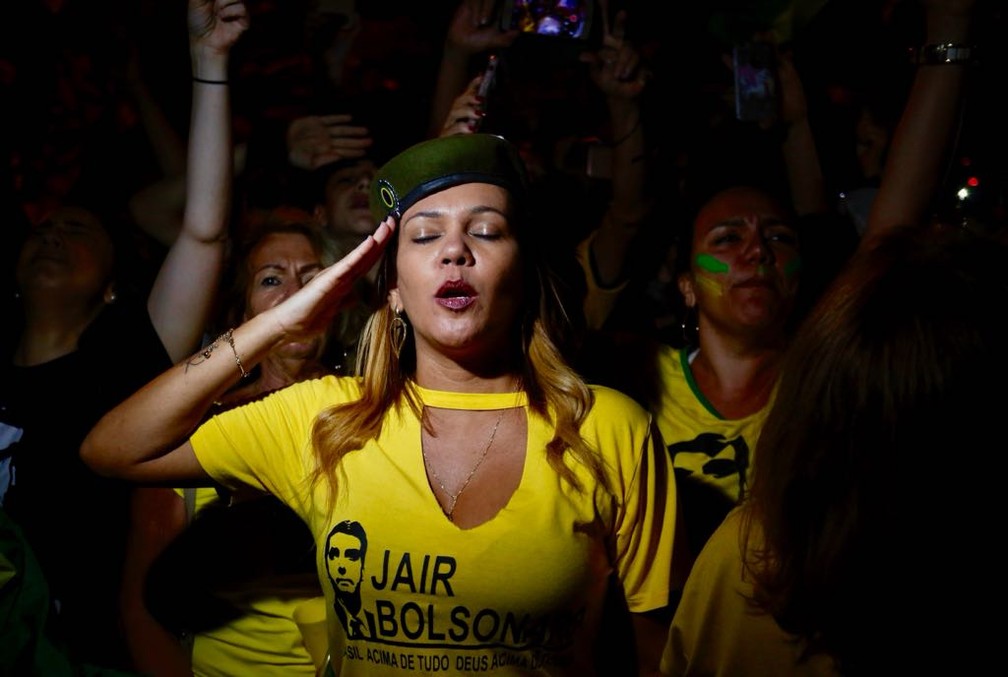 Mulher bate continência durante festa pela eleição de Bolsonaro na Barra de Tijuca, Rio — Foto: Marcos Serra Lima/G1