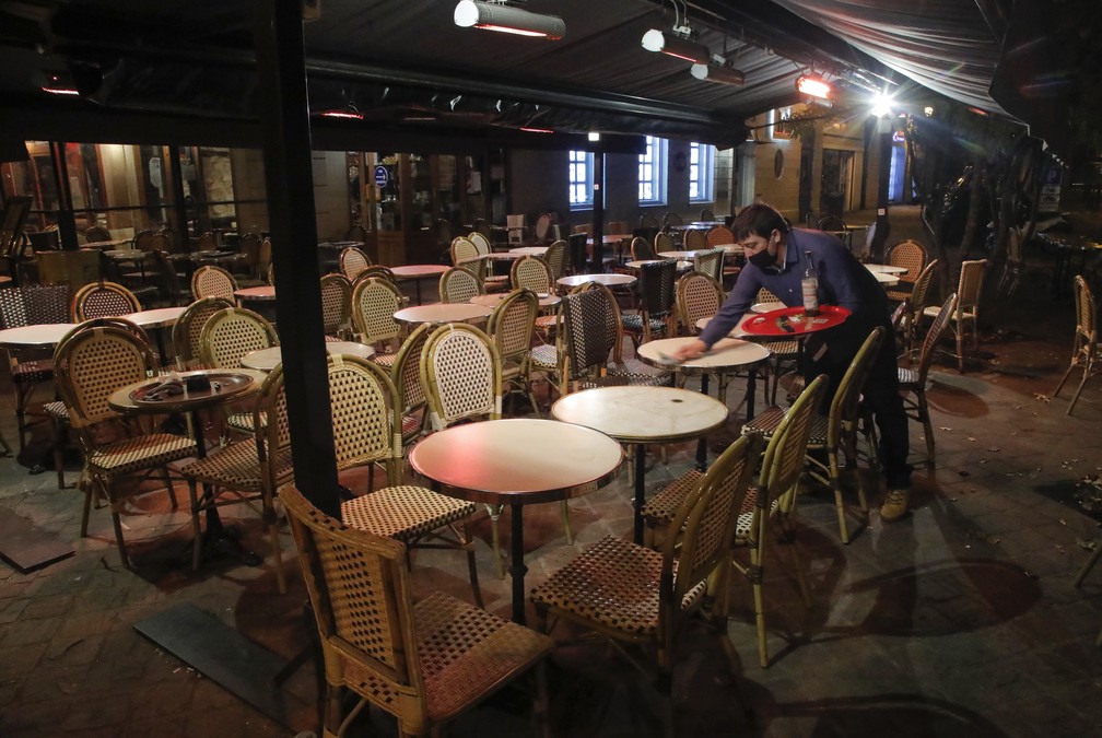 Garçom limpa mesa de bistrô em Paris, na França, em 16 de outubro de 2020. Novas restrições forçaram restaurantes, cinemas e teatros a fechar na capital francesa devido a um toque de recolher para frear o avanço da segunda onda do novo coronavírus. — Foto: Michel Euler/AP