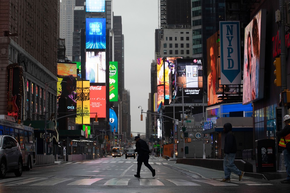 Homem caminha pela Times Square, em Nova York (EUA), quase vazia na manhã de segunda-feira (23)  — Foto: Mark Lennihan/AP