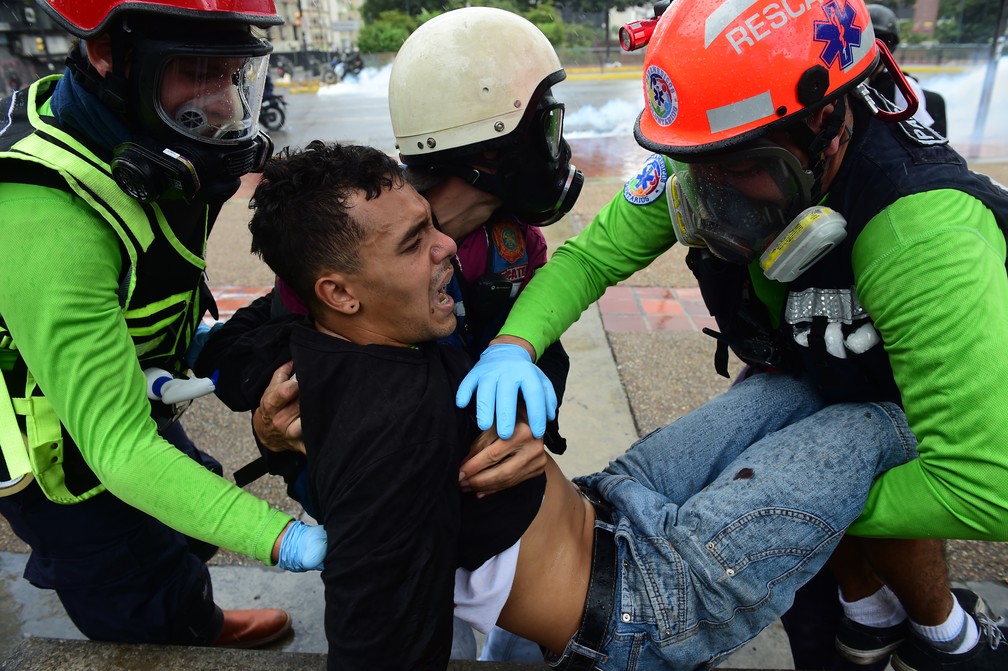 Manifestante contra governo é ajudado por médicos após se ferir na Venezuela (Foto: Ronaldo Schemidt/AFP)