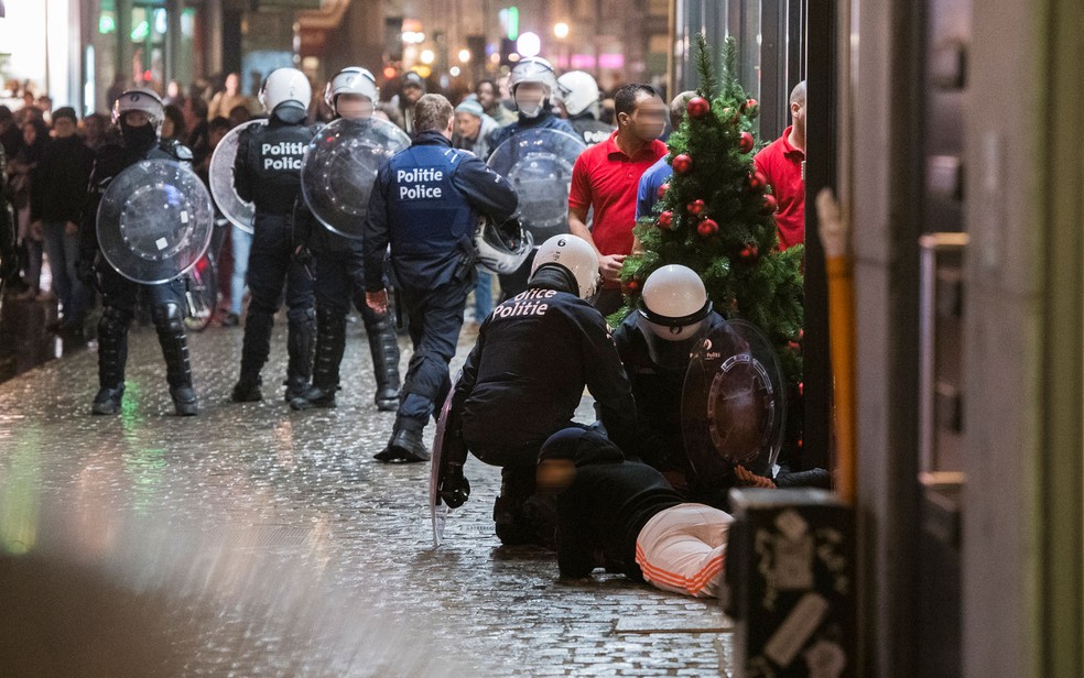 Policiais detêm uma pessoa no chão durante tumulto no centro de Bruxelas na quarta-feira (15) (Foto: Laurie Dieffembacq/Belga/AFP)