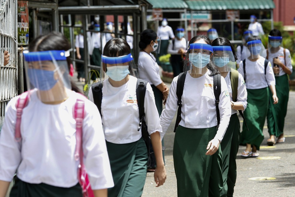Estudantes voltam às aulas com máscaras e escudos faciais em Rangun, Mianmar, para se protegerem contra a Covid-19 no dia de reabertura das escolas públicas, nesta terça (21). — Foto: Sai Aung Main / AFP
