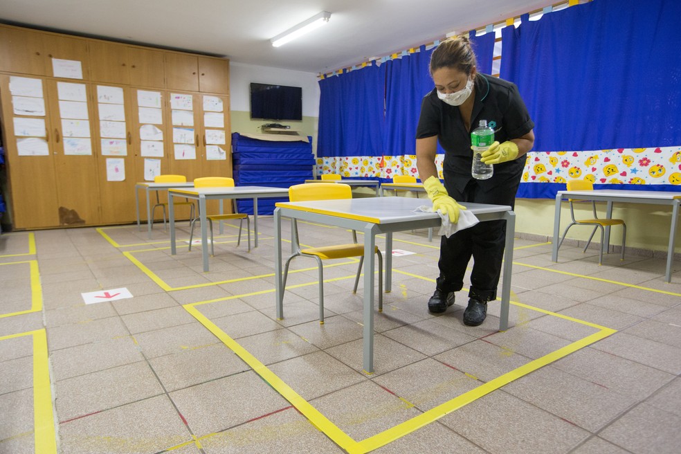 Funcionária limpa mesas para demonstrar medidas de limpeza para a volta às aulas na rede municipal de ensino de São Paulo, em evento da prefeitura na Escola Municipal de Educação Infantil (EMEI) São Paulo, na Vila Clementino, em foto do dia 14 de janeiro. — Foto: TIAGO QUEIROZ/ESTADÃO CONTEÚDO