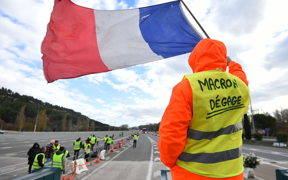 Manifestante veste colete amarelo com os dizeres 'Macron cai fora' — Foto: Sylvain Thomas/AFP
