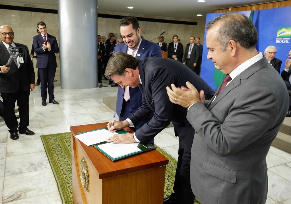 O presidente Jair Bolsonaro, nesta terça-feira (18), ao sancionar a lei que visa coibir fraudes previdenciárias — Foto:  Isac Nóbrega/PR
