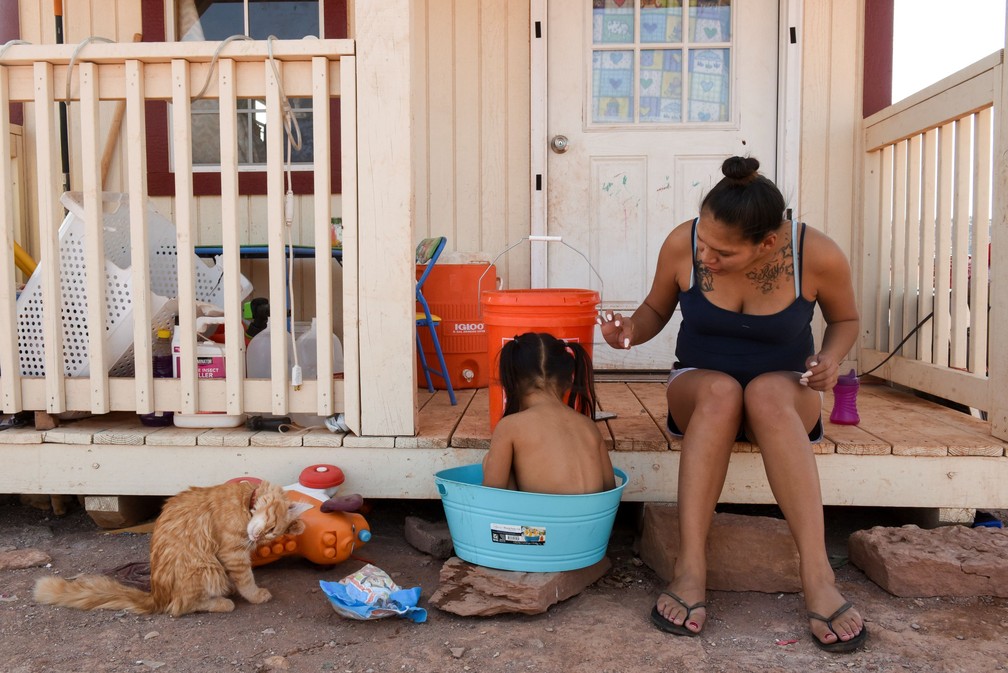 Summer Weeks, de 23 anos, dá banho em sua filha Ravynn, de dois anos. 'Não me importo de viver sem água corrente e eletricidade. Cresci assim, estou acostumada. Vim para cá porque queria que meus filhos tivessem o mesmo tipo de educação que eu tive', disse ela. — Foto: Stephanie Keith/Reuters