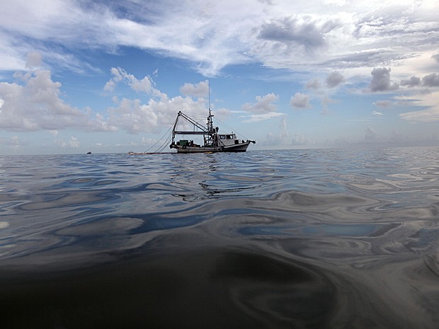Imagem de junho de 2010, em Cat Bay, Louisiana, mostra barco com lança e material absorvente para retirar o petróleo da água após vazamento da plataforma Deepwater Horizon, da BP, no Golfo do México (Foto: Joe Raedle/Getty Images North America/Arquivo AFP)