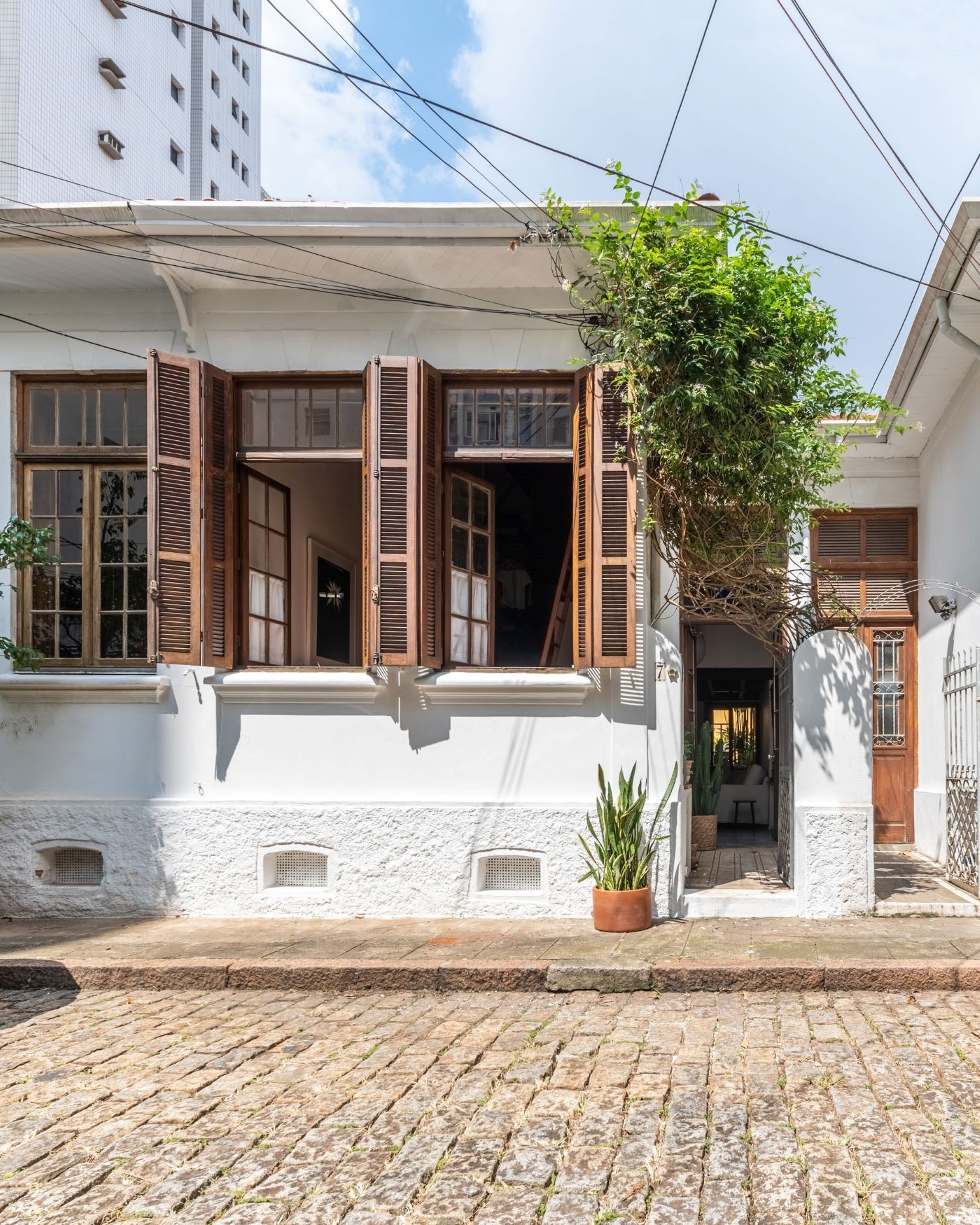 A casa tradicional do século 20 tem a entrada pela lateral e janelões voltados para a rua, em uma vila (Foto: Guilherme Pucci / Divulgação)
