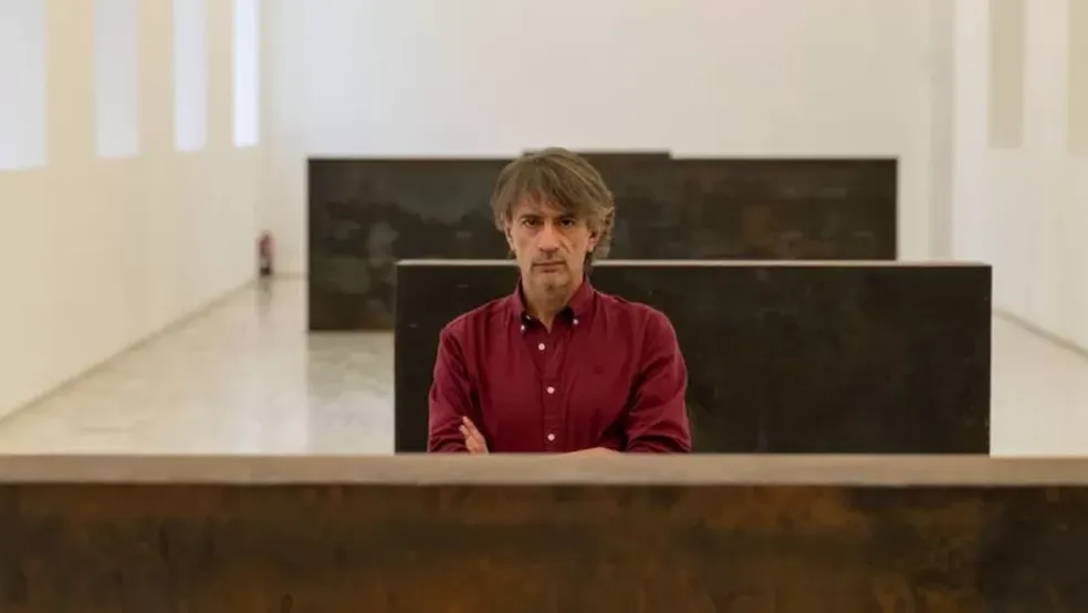 O escritor Juan Tallón entre os blocos da escultura de Richard Serra — Foto: BBC