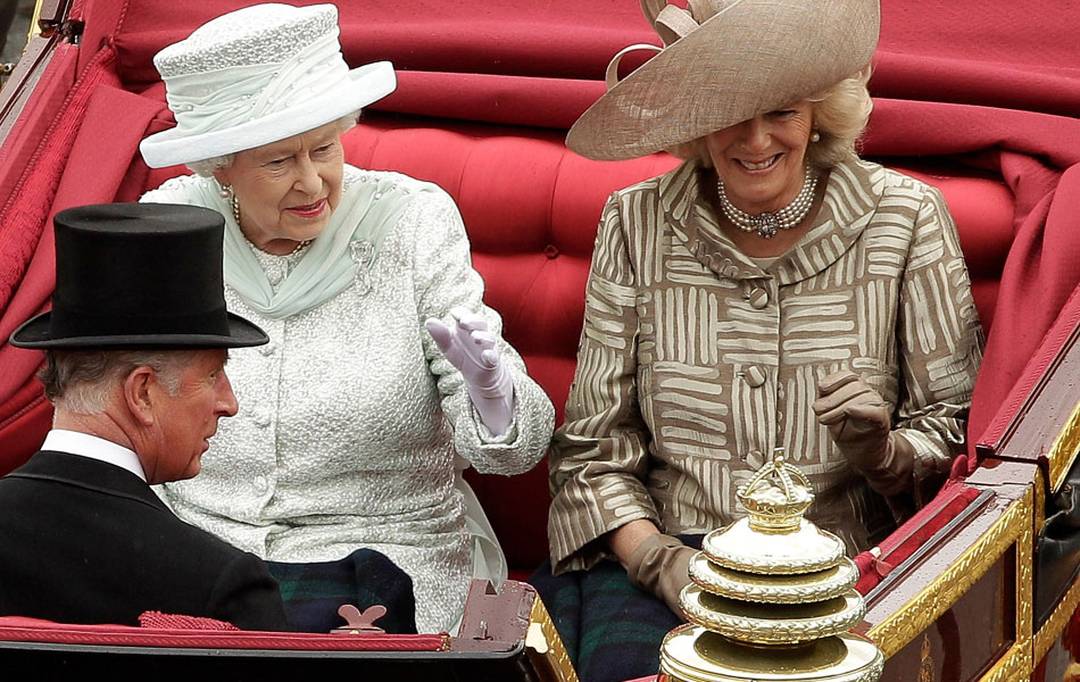 Rainha  acompanhada em carruagem por seu filho, Charles, e a nora, Camilla