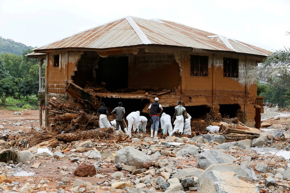 Equipe de resgate busca sobreviventes entre destroços ao redor de uma casa destruída por um deslizamento ocorrido em meio a tempestade em Freetown, Serra Leoa (Foto: Afolabi Sotunde/Reuters)