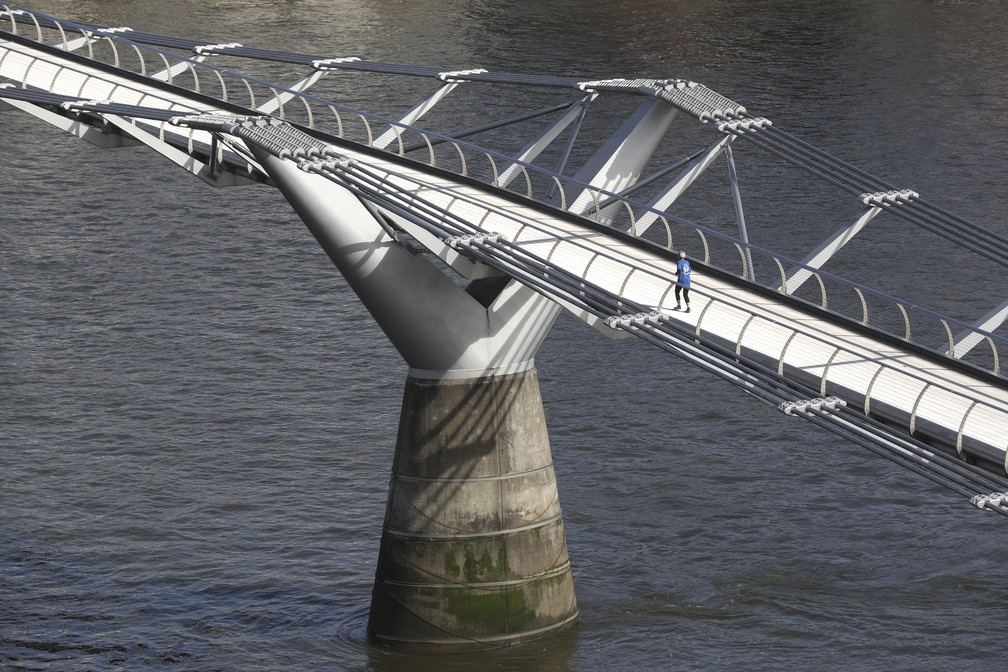 Uma pessoa atravessa a ponte Millennium em Londres, ter&ccedil;a-feira (17). As autoridades brit&acirc;nicas intensificaram as medidas de sa&uacute;de p&uacute;blica na segunda-feira, dizendo &agrave;s pessoas que est&atilde;o nos grupos considerados mais vulner&aacute;veis &agrave; doen&ccedil;a grave da Covid-19 que fiquem em casa por tr&ecirc;s meses. &mdash; Foto: Jonathan Brady/PA via AP