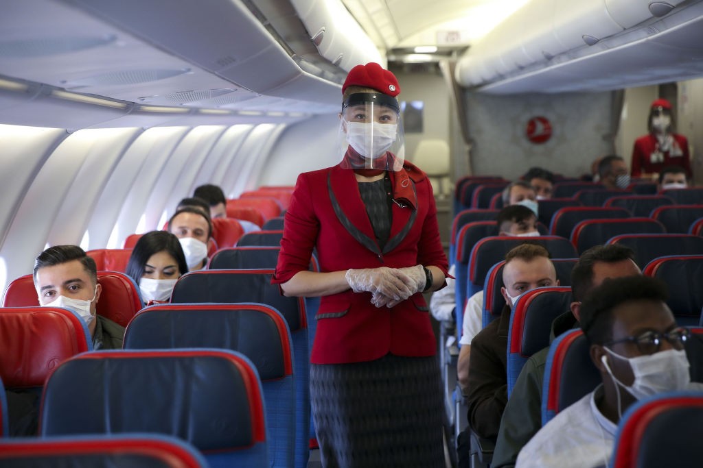 Comissária de bordo usa máscara e luvas e novos protocolos de higiene e distanciamento devem ser adotados pelas companhias aéreas (Foto: Getty Images)