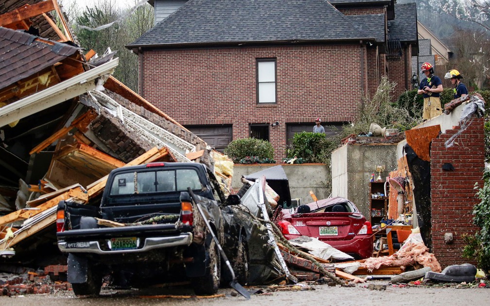 Bombeiros inspecionam escombros de casa destruída por tornado em Birmingham, Alabama, na quinta-feira (25) — Foto: AP Photo/Butch Dill