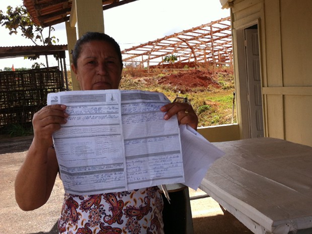 Maria de Lurdes da Silva, moradora do canteiro, mostra documentos que pedem a saída dela do local (Foto: Gabriel Luiz/G1)