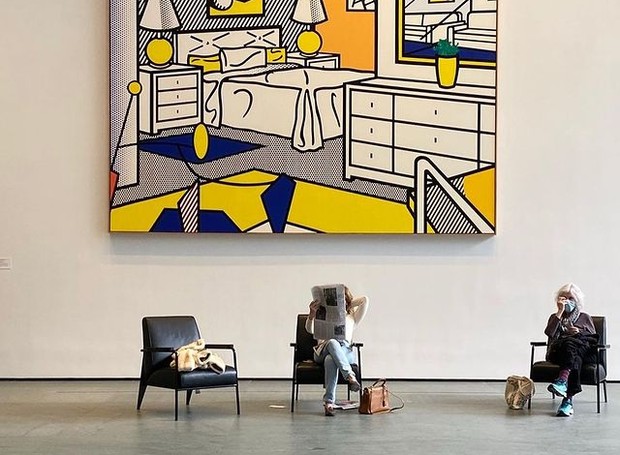O Museum of Modern Art em Nova York reabriu as portas com as medidas obrigatórias de segurança. Na foto, duas pessoas relaxam no lobby, em frente ao quadro "Interior with Mobile", de Roy Lichtenstein, feito em 1992 (Foto: Reprodução / Instagram)