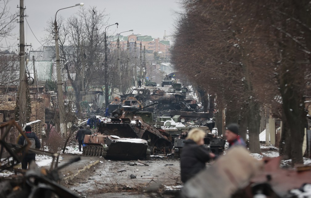 Moradores observam restos de veículos militares perto de Kiev — Foto: Serhii Nuzhnenko/AP