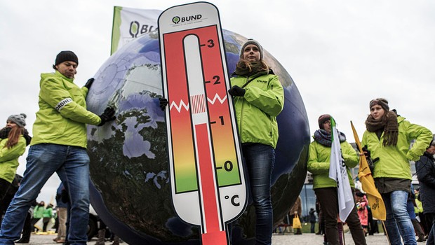 Uma mulher segura um termômetro durante encontro de ativistas na Marcha Global do Clima, que aconteceu em Berlim um dia antes do início da COP21 (Foto: Carsten Koall / Stringer/ Getty Images)