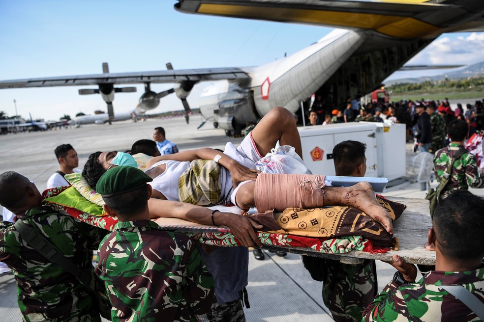 Um homem ferido é evacuado em um avião militar no Aeroporto de Palu, na Indonésia — Foto: REUTERS