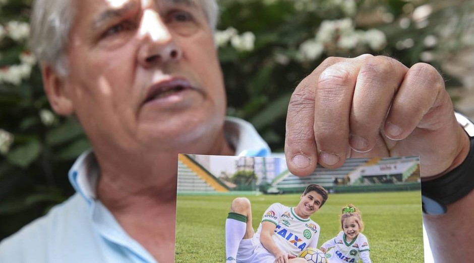 Osmar Machado, pai do jogador da Chapecoense Filipe Machado, morto no desastre de avião na Colômbia, mostra foto do filho e da neta Antonella no gramado da Arena Condá, estádio do clube    (Foto:  Andre Penner / AP)