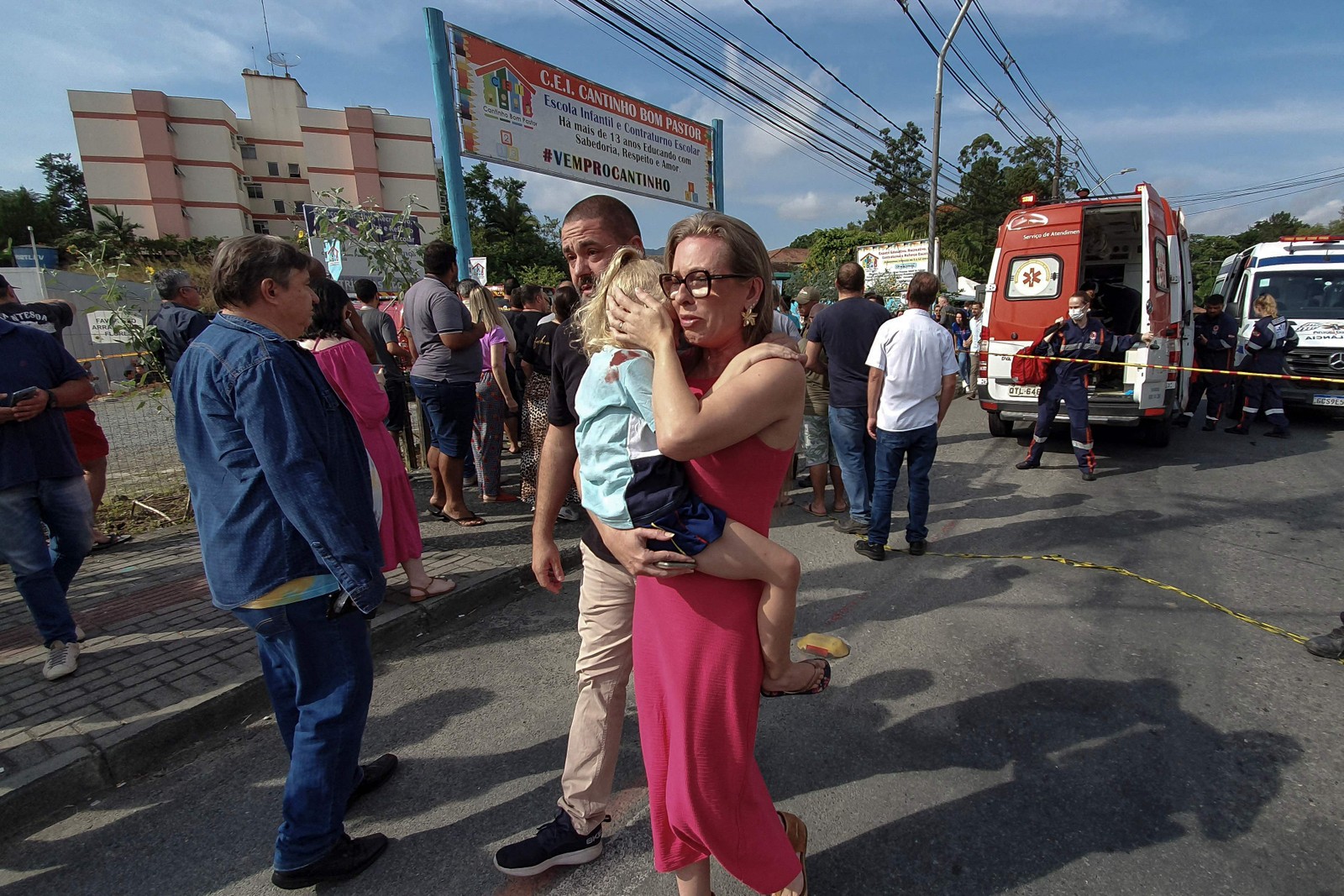 Uma mulher carrega uma criança nos braços do lado de fora da pré-escola onde um agressor matou quatro crianças com uma arma branca, em Blumenau, Santa Catarina — Foto: Patrick RODRIGUES / NSC Total / AFP