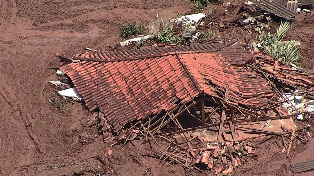Casa fica abaixo da lama após rompimento de barragem — Foto: TV Globo