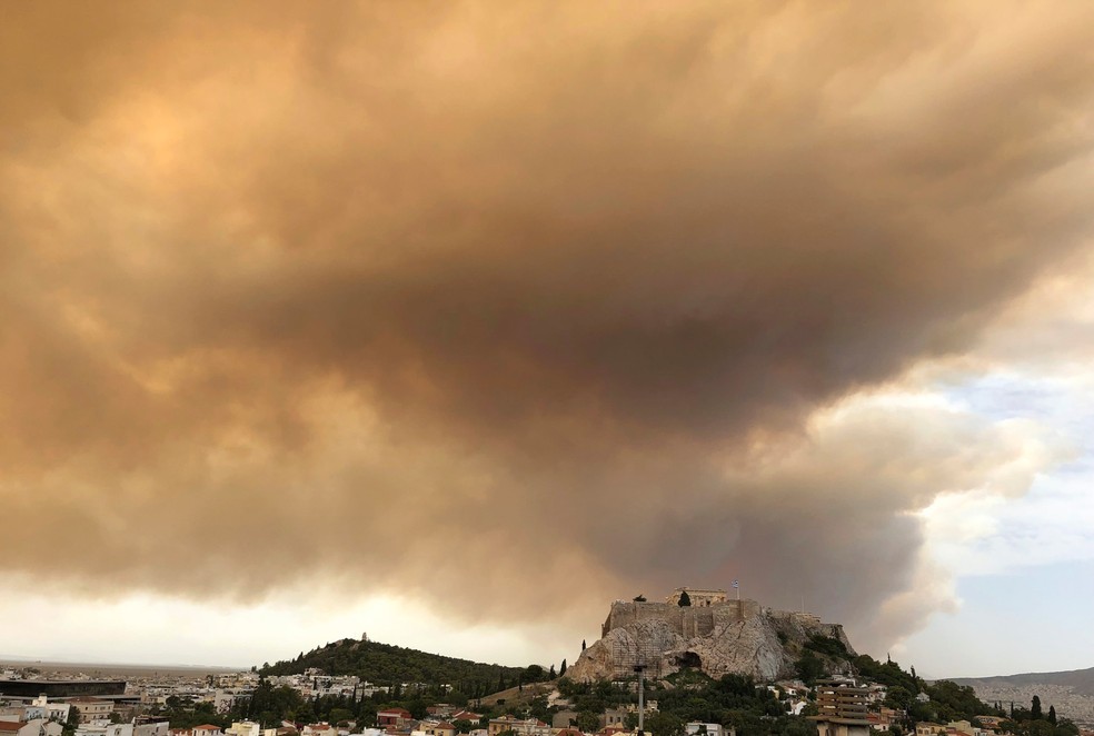 Uma grande nuvem deixa o céu dourado na antiga cidade de Acropolis, no oeste de Atenas, na Grécia, durante um incêndio flroestal (Foto: Theodora Tongas/AP)