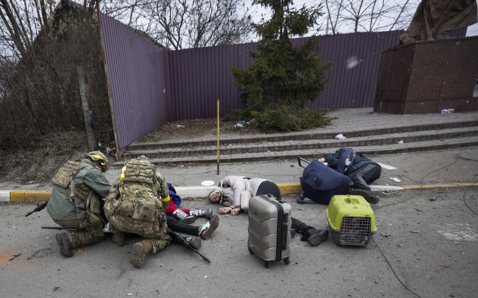 Soldados ucranianos socorrem homens feridos na cidade de Irpin neste domingo, 06 — Foto: Andriy Dubchak/AP Photo