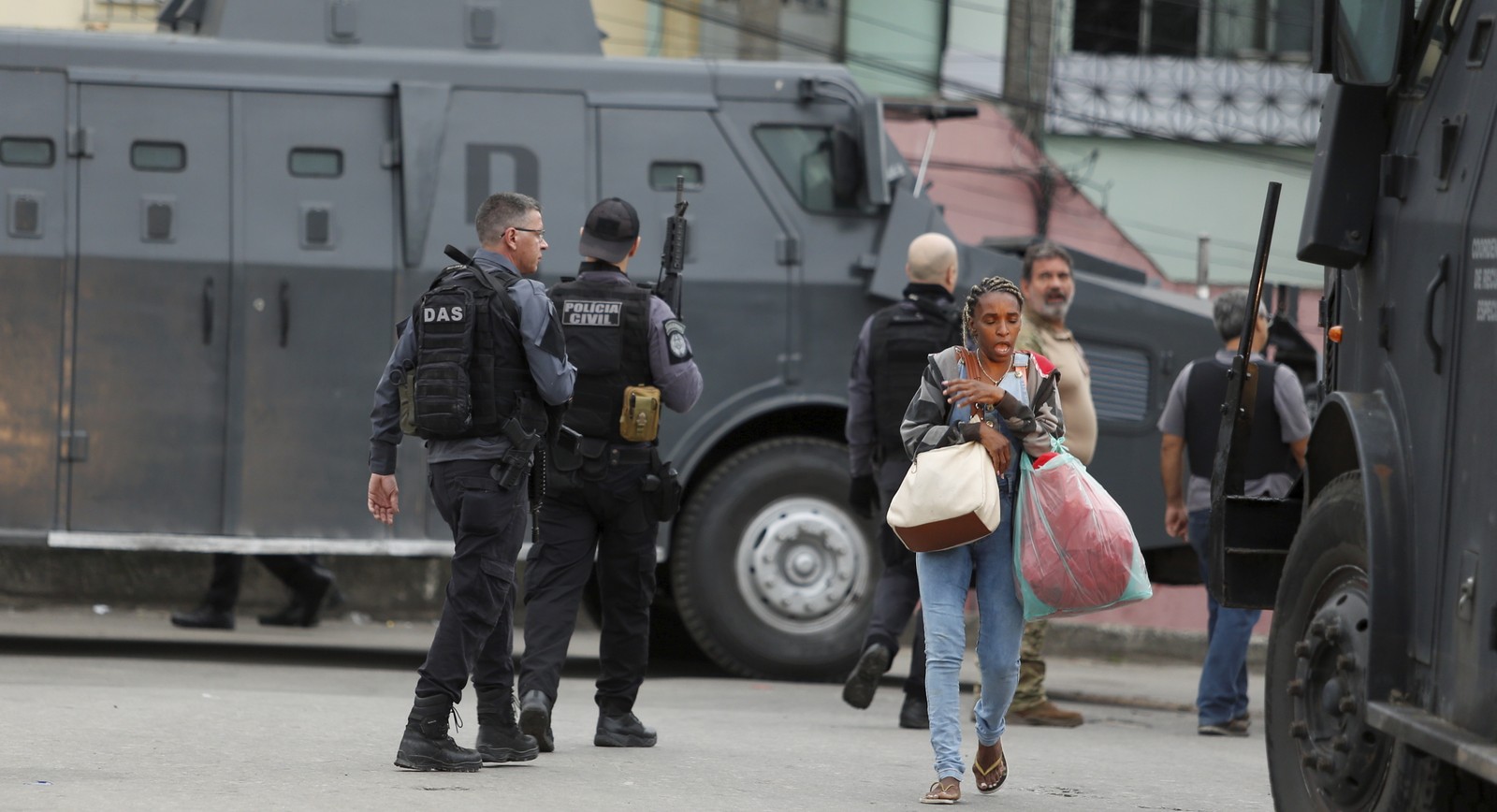 Moradora da Cidade de Deus caminha por rua ocupada por policiais fortemente armados — Foto: Fabiano Rocha / Agência O Globo
