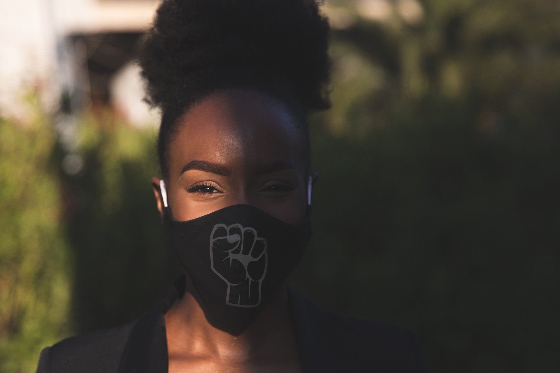 Woman wearing a black face mask with a fist printed on it, protesting for human rights of black people. (Foto: Getty Images)