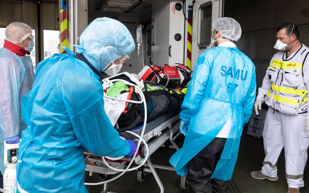Paciente com Covid-19, trazido da região de Lyon, onde hospitais estão lotados, é recebido por equipe do hospital Hautepierre, em Strasbourg, na França, na quinta-feira (12) — Foto: AP Photo/Jean-François Badias