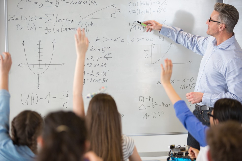 Formação ideal de professor deve incluir bacharelado e licenciatura. Na foto, homem ensina matemática a alunos.  — Foto: CAIA IMAGE/SCIENCE PHOTO LIBRARY via AFP