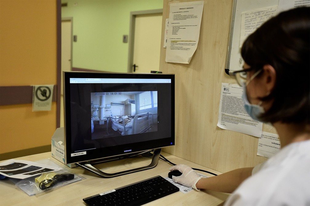 1º de abril - Enfermeira acompanha pela tela as imagens de um robô que monitora pacientes com coronavírus no hospital Circolo em Varese, na Itália — Foto: Flavio Lo Scalzo/Reuters